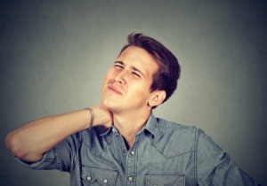 Stressed unhappy young man with bad neck pain