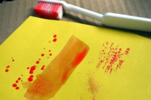 Use Old Toothbrushes in Your Craft Box - toothbrush and paint smear and spatters on yellow paper