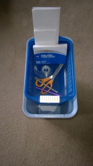 A trash can with a top container for holding mailing supplies.
