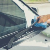 A person cleaning a windshield with a blue cloth.
