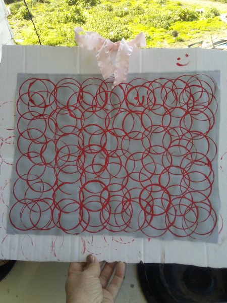 Fabric Stamp Art - white fabric with red overlapping paint circles mounted to a piece of cardboard