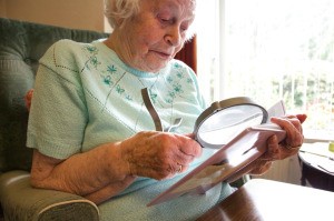 Senior woman using a large magnifying glass to read.