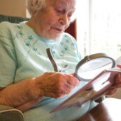 Senior woman using a large magnifying glass to read.