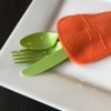Felt Carrot Utensil Holder - green plasticware protruding from carrot pocket onto corner of plate