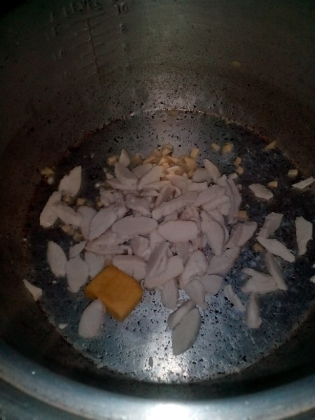 Ginger and garlic being sauteed in a pan.