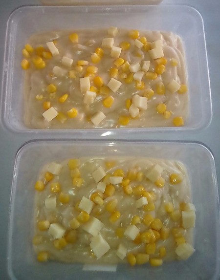 pudding in small containers with corn and cheese on top