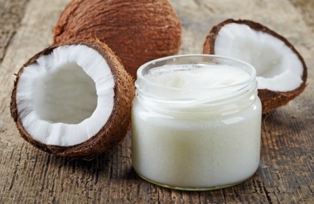 A jar of coconut oil next to a cracked coconut.