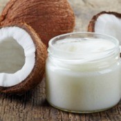 A jar of coconut oil next to a cracked coconut.