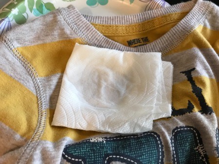 White Vinegar for Removing Sticker Residue from Clothing - paper towel with vinegar sitting on the spot