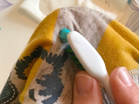 White Vinegar for Removing Sticker Residue from Clothing - having your finger under the fabric helps while brushing