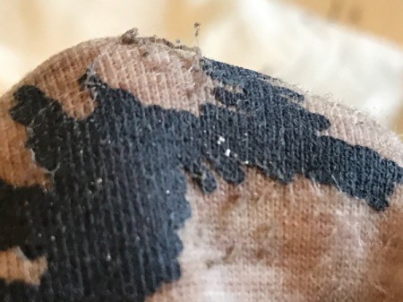 White Vinegar for Removing Sticker Residue from Clothing - closeup of residue rolling up