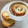 A bowl of French Onion soup with melted cheese over bread.