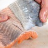 A person removing the skin from a salmon filet.
