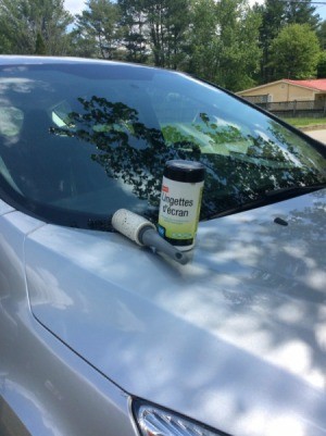 A clean car with a lint roller and cleaning wipes on the hood.