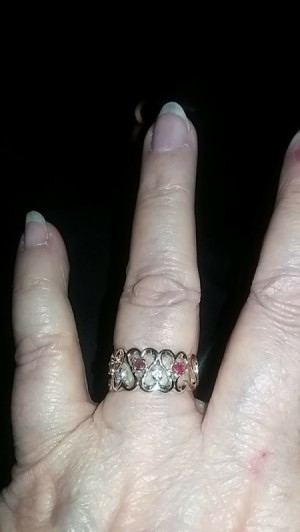 A gold and gemstone ring on a woman's finger.