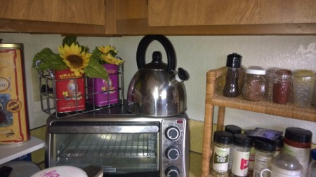 A kettle on top of a toaster oven in a small kitchen.