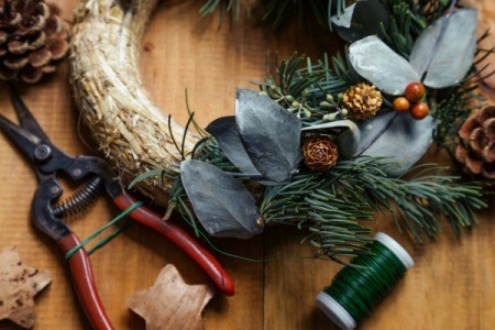 A handmade wreath being assembled, with tools and materials.