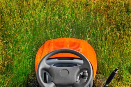 A riding lawnmower, from the view of the seat.