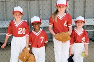 A children's baseball team with red tops and white pants.