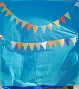 A background placed on a wall with bunting to be used as a photo booth.