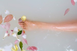 A lower leg in a bathtub, filled with milk and flowers.