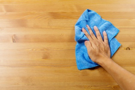 A woman rubbing oil on a wood table.