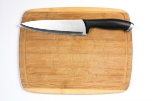 A bamboo cutting board with a sharp knife.
