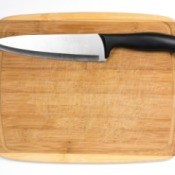 A bamboo cutting board with a sharp knife.