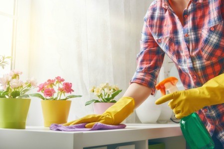 A woman spraying cleaner on a white counter.