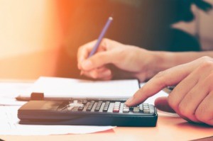 A woman with a calculator and notepad, calculating bills.