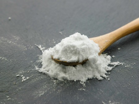 A white powder on a spoon, either baking soda or baking powder.