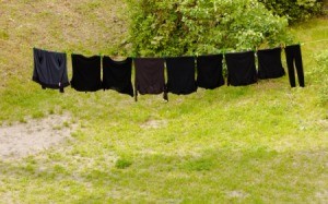 A row of black clothing on a clothesline.