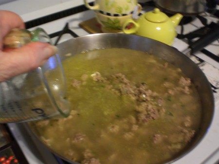 Adding broth to pan