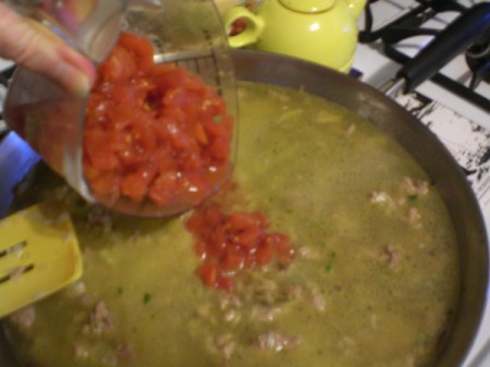 adding tomatoes to pan