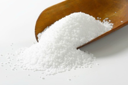 A scoopful of salt on a white surface.