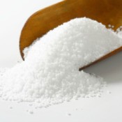 A scoopful of salt on a white surface.