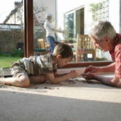 A man and his grandchild, counting change on the floor.