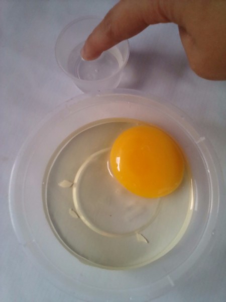 Using your finger to remove eggshell from the cracked egg contents.