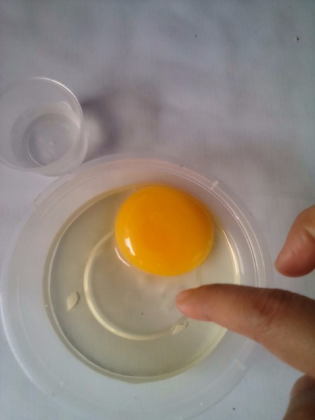 Using your finger to remove eggshell from the cracked egg contents.