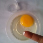 Using your finger to remove eggshell from the cracked egg contents.