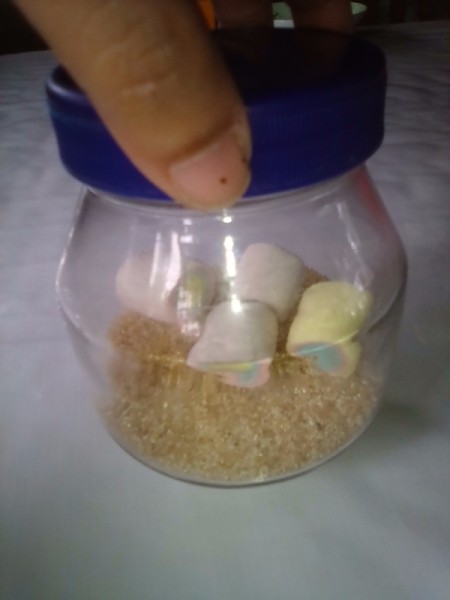 Marshmallows being placed in a glass jar.