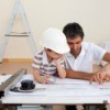 A boy at work with his father, looking at blueprints.