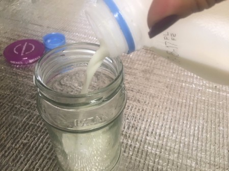 Pouring milk into a glass jar to be frothed.