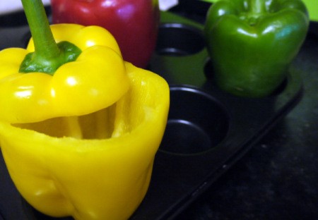 Tri-colored sweet peppers placed in a muffin tin, ready for stuffing.