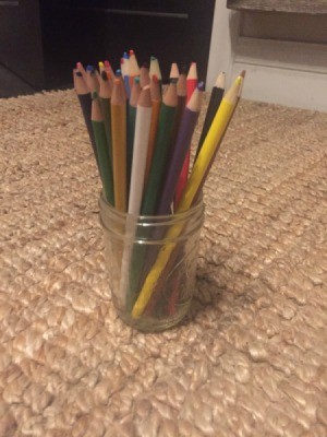 A mason jar used to store colored pencils.