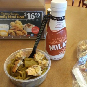 A deli meal consisting of a salmon patty and green beans.