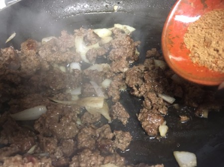 adding seasoning to burger and onion