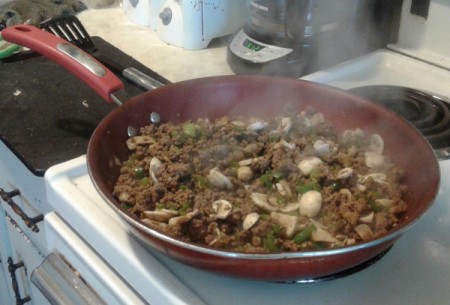 cooked ground beef, mushrooms and green peppers in skillet