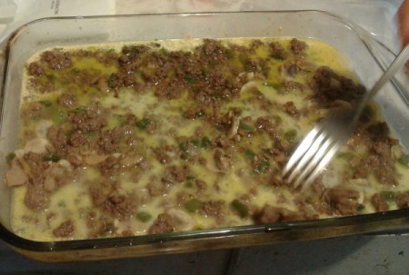 forking Ground Beef Scalloped Potatoes in baking dish