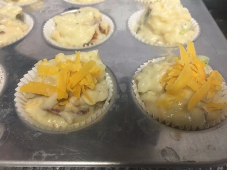 batter in muffin tins with cheese on top